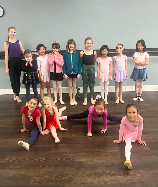 Dance instructor and young dancers posing together in the studio